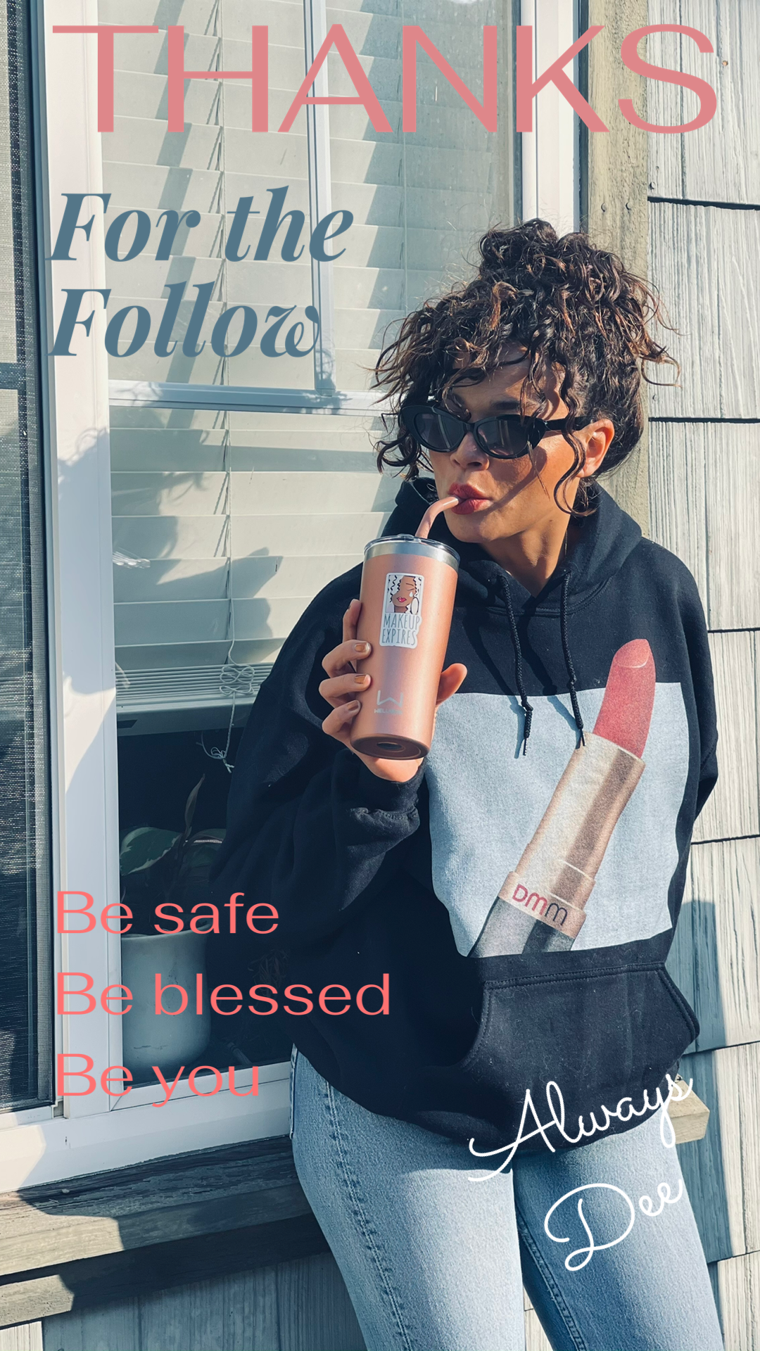 Young woman drinking from a straw.  The cup has makeup does expire sticker.  Se wears a navy blue hoodie with DMM lipstick